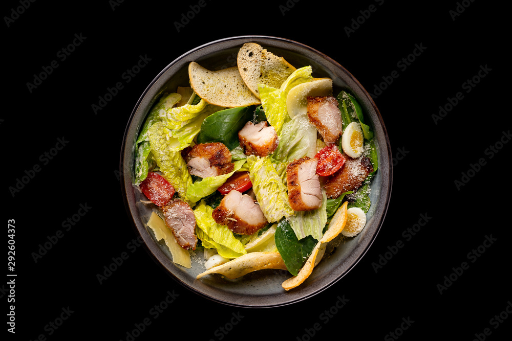Top view image of caesar salad served in an iron pan isolated at black background. Top view image of caesar salad served in an iron pan isolated at black background.
