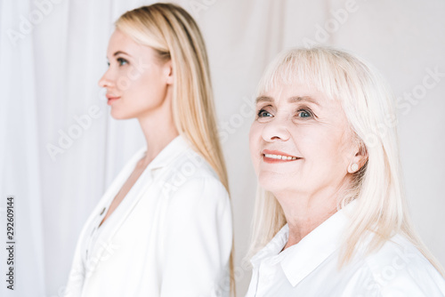 selective focus of blonde grandmother and granddaughter together in total white outfits