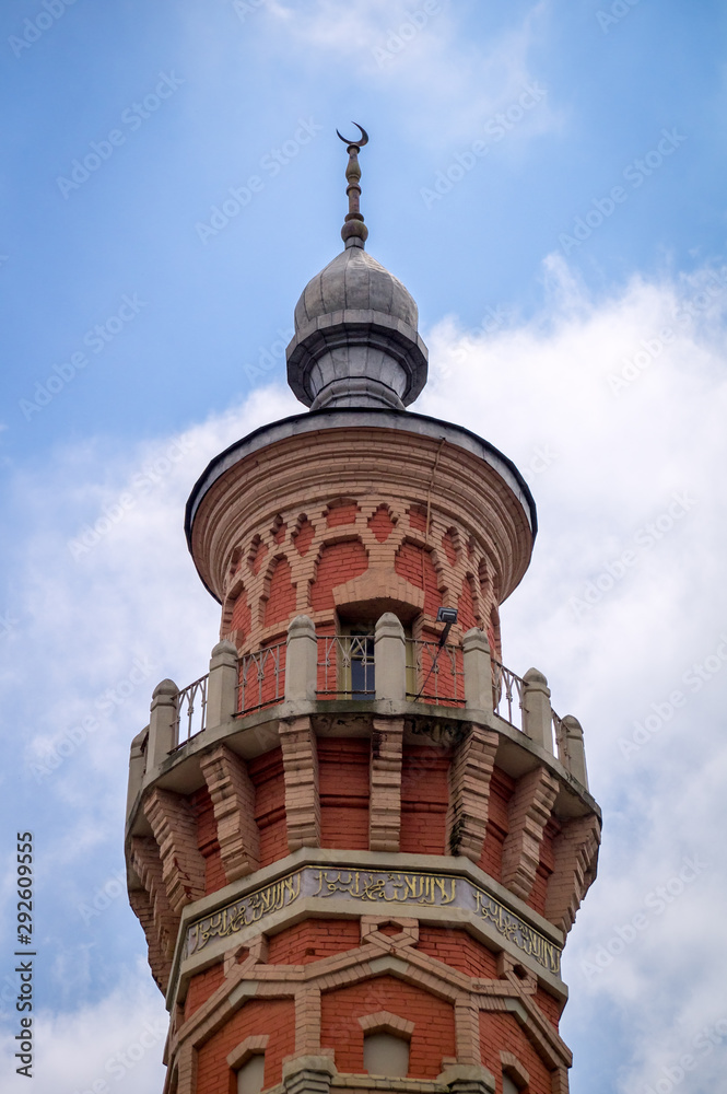 Top of the minaret of the Sunni Mukhtarov Mosque in Vladikavkaz city, North Ossetia Alania, Russia in front of bright blue sky with white clouds