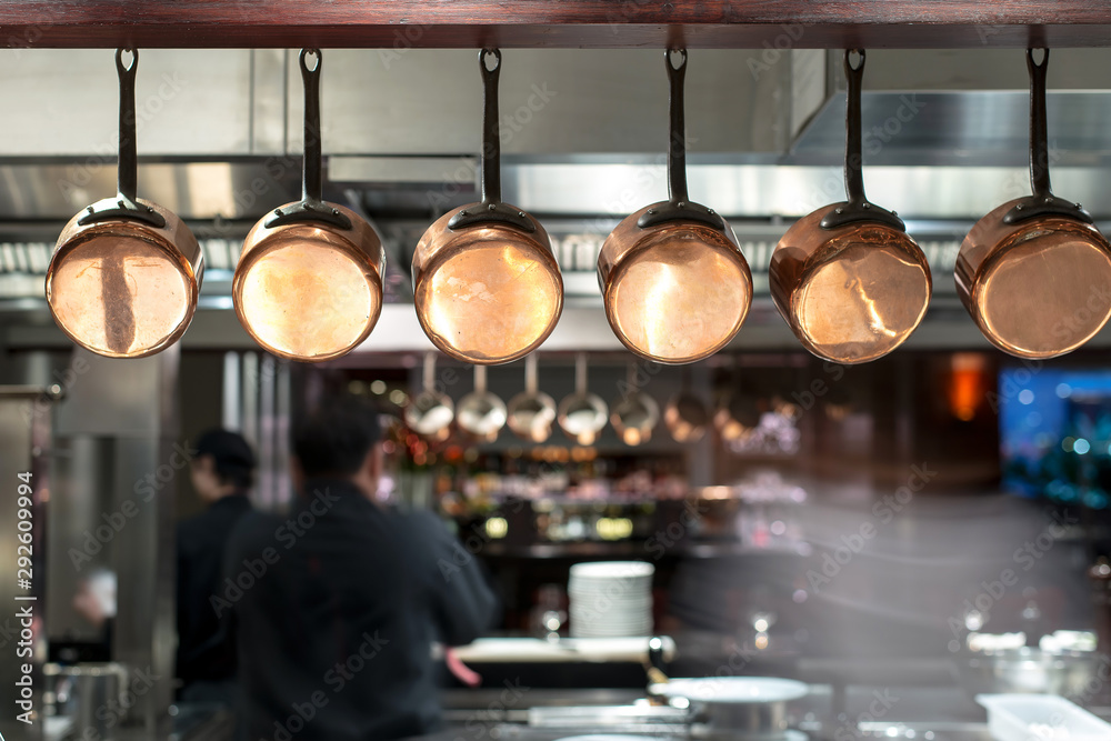 saucepans hanging from a rack in busy kitchen saucepans hanging from a rack in busy kitchen