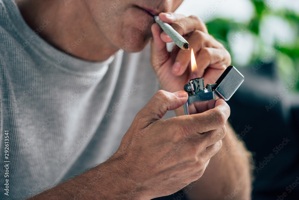 Fototapeta premium cropped view of man lighting up blunt with medical cannabis