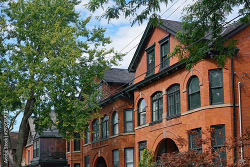 Photography Tree lined street with large old brick houses with gables