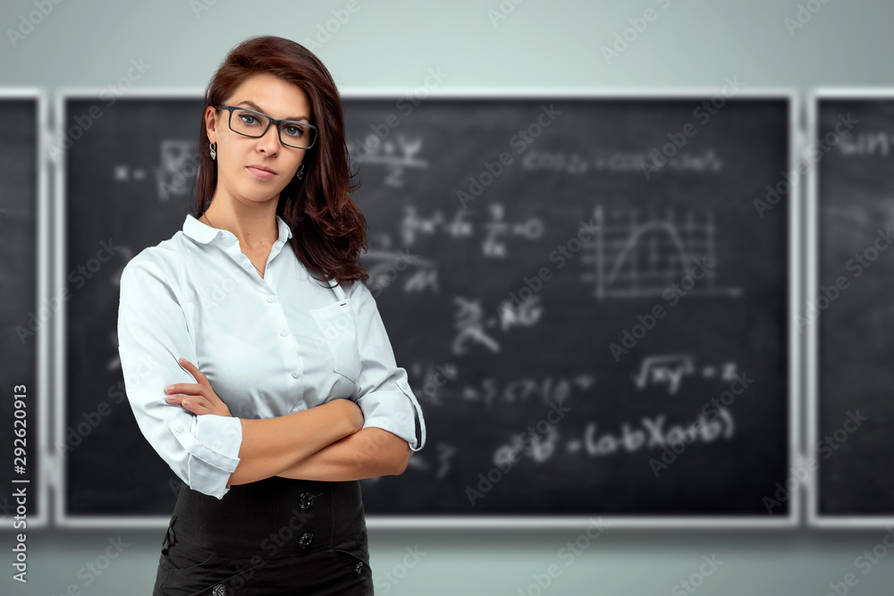 Portrait of a young beautiful teacher on the background of the school blackboard. Teacher's Day Knowledge Day back to school study online learning. Portrait of a young beautiful teacher on the background of the school blackboard. Teacher's Day Knowledge Day back to school study online learning.