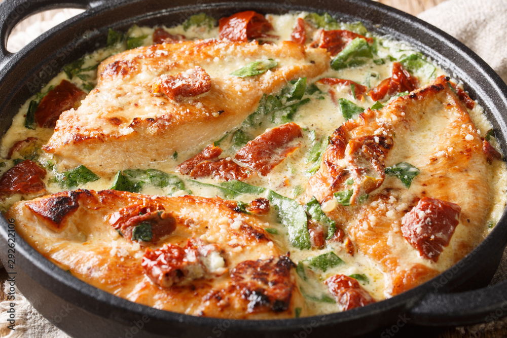 Tasty chicken fillet with sun-dried tomatoes and spinach in cheese sauce close-up in a pan. horizontal Tasty chicken fillet with sun-dried tomatoes and spinach in cheese sauce close-up in a pan. horizontal