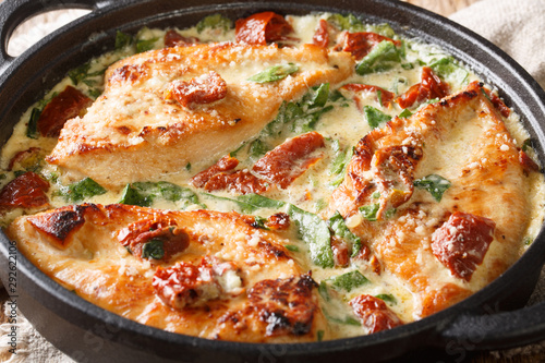 Tasty chicken fillet with sun-dried tomatoes and spinach in cheese sauce close-up in a pan. horizontal