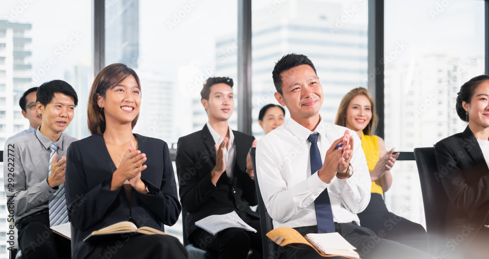 Young business people clapping hands during meeting in office for their success in business work Young business people clapping hands during meeting in office for their success in business work