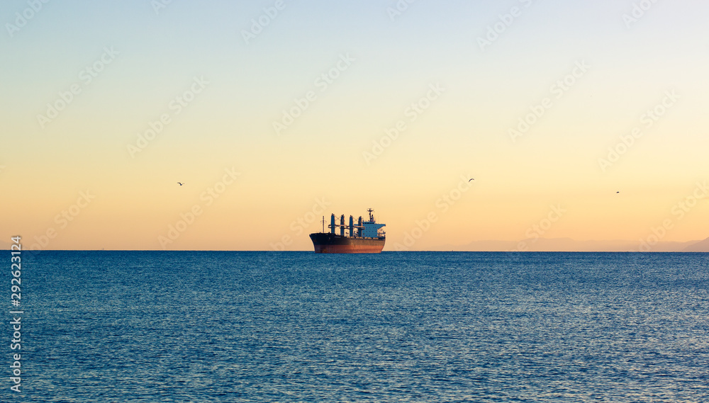 cargo ship industrial transport on sea horizon idyllic scenic landscape view on evening soft colors sky peaceful background, wallpaper poster empty copy space for text 