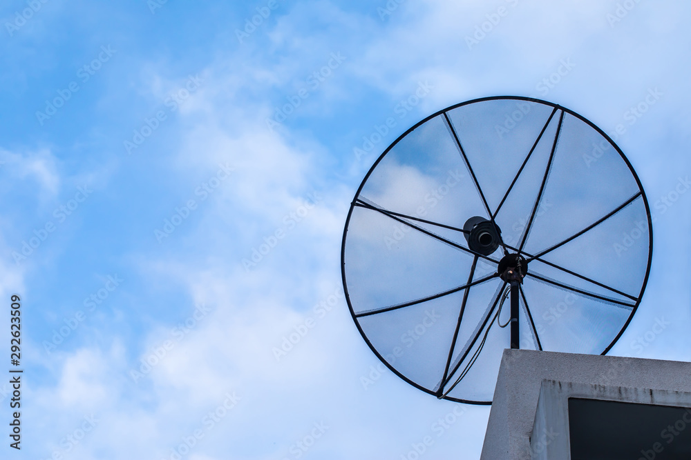 Satellite dish on roof with blue sky and cloudy.