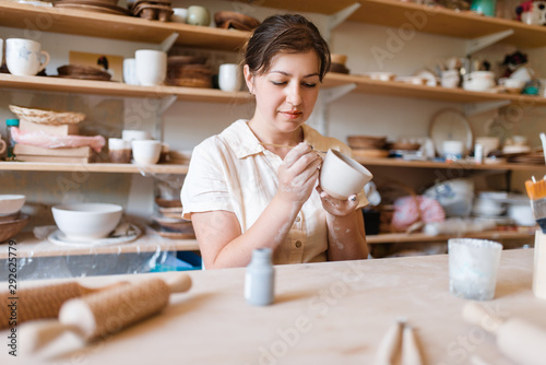Female master paints a pot, pottery workshop