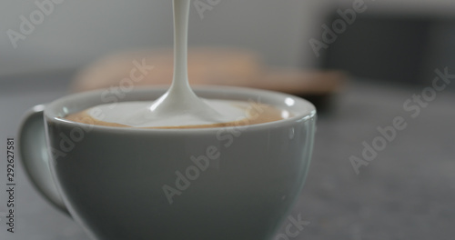 pouring steamed milk anto espresso to make capuccino photo