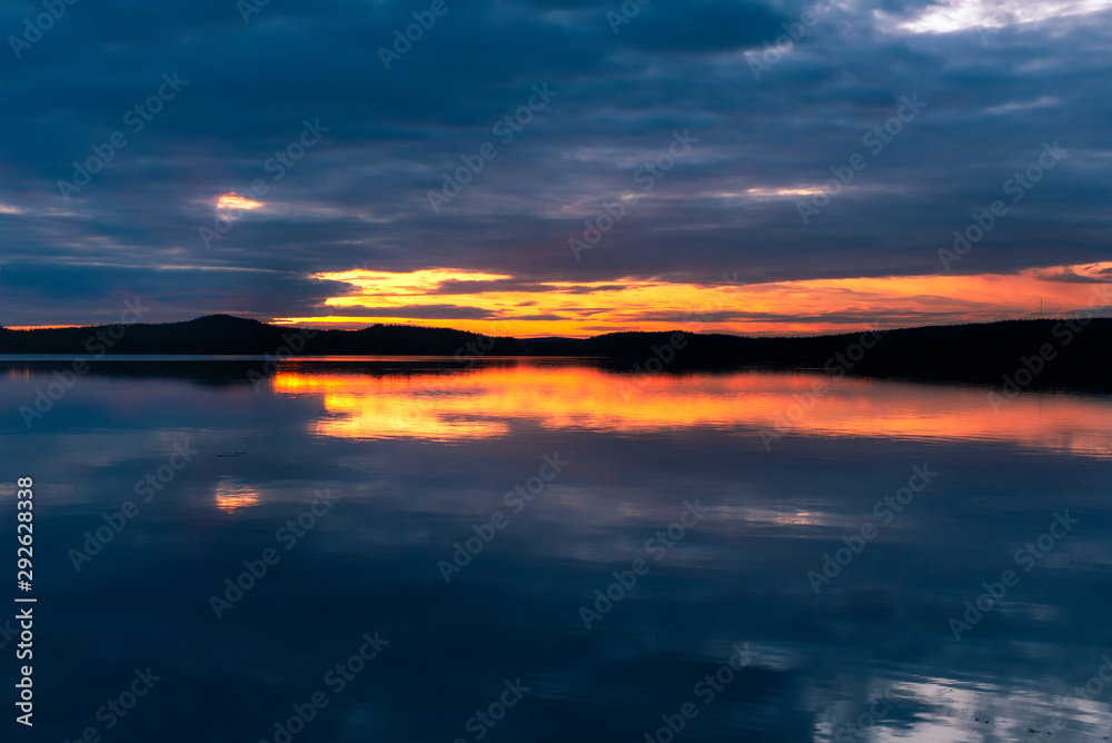 Water reflections at midnight sun at serene lake in finlandd