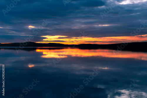 Water reflections at midnight sun at serene lake in finlandd