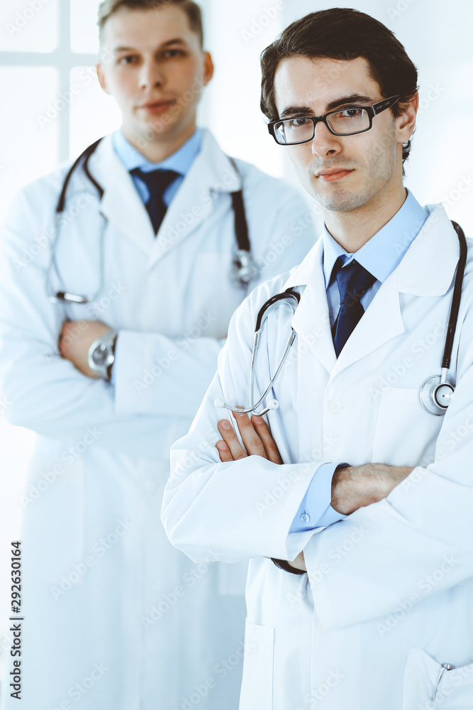 Doctor man standing straight with colleague at background. Group of doctors. Perfect medical service in clinic. Medicine and healthcare concepts Doctor man standing straight with colleague at background. Group of doctors. Perfect medical service in clinic. Medicine and healthcare concepts
