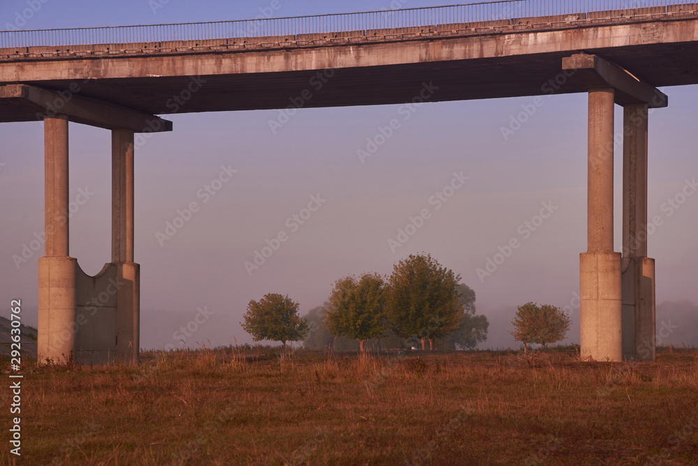 Old concrete collapsing bridge autumn in the autumn foggy morning passing over the meadow. Old concrete collapsing bridge autumn in the autumn foggy morning passing over the meadow.