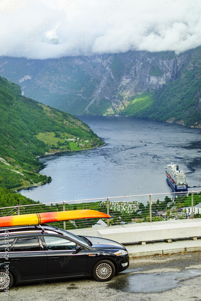 Car with canoe on top roof against fjord
