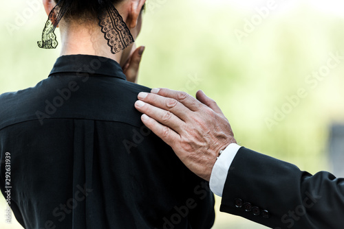 cropped view of elderly man touching woman on funeral photo