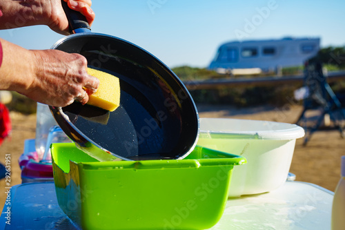 Woman washing dishes in bowl, capming outdoor photo