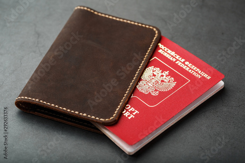 Brown leather cover with a red passport on a dark background