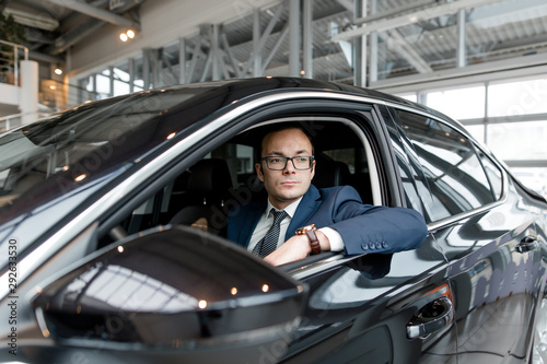 Male driver sitting in a new black sedan. Buying a new car in the showroom © pantovich