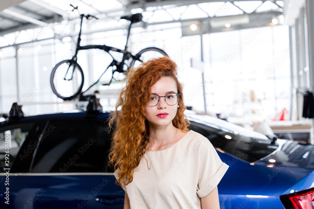 Redheaded girl standing in the background of the car