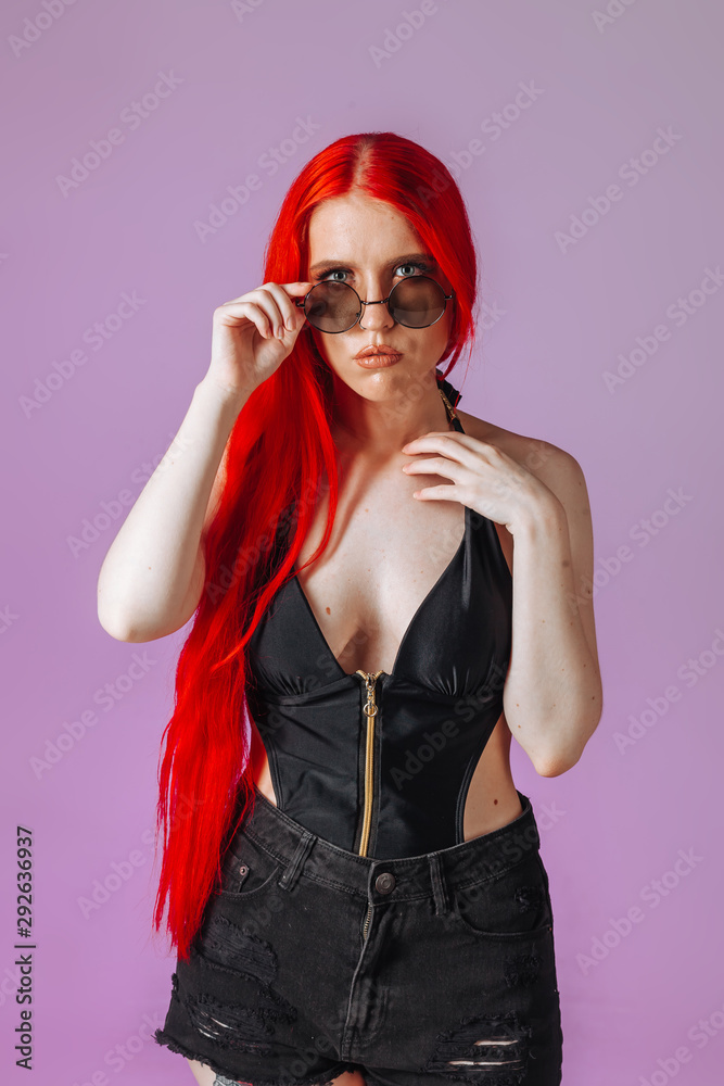 Portrait of a girl with red long hair in round glasses on a pink background Portrait of a girl with red long hair in round glasses on a pink background