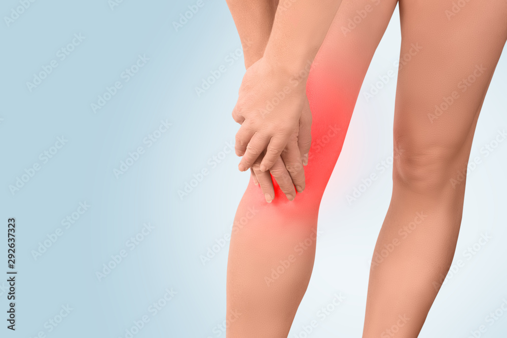 Legs female with a focus of the disease in the knee joint, the woman holds the hands of the sore spot, highlighted in red Legs female with a focus of the disease in the knee joint, the woman holds the hands of the sore spot, highlighted in red