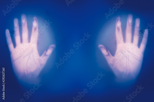 Hands on misted frosted glass, danger and horror of the paranormal, blurred focus