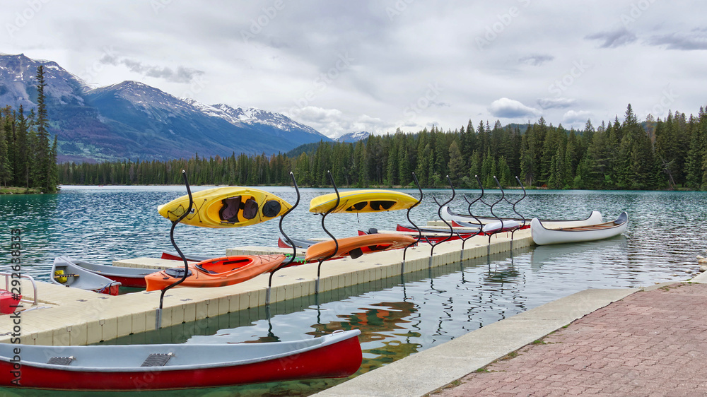 Naklejka premium kayaks and canoes at the pier on a mountain lake surrounded by coniferous forest in Rocky mountains, Beauvert lake Jasper National Park, Alberta, Canada – Версия 2