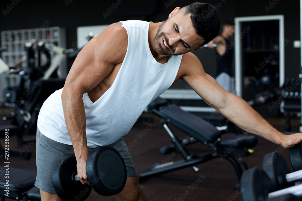 Fit and muscular man trains with dumbbells. Fit and muscular man trains with dumbbells.