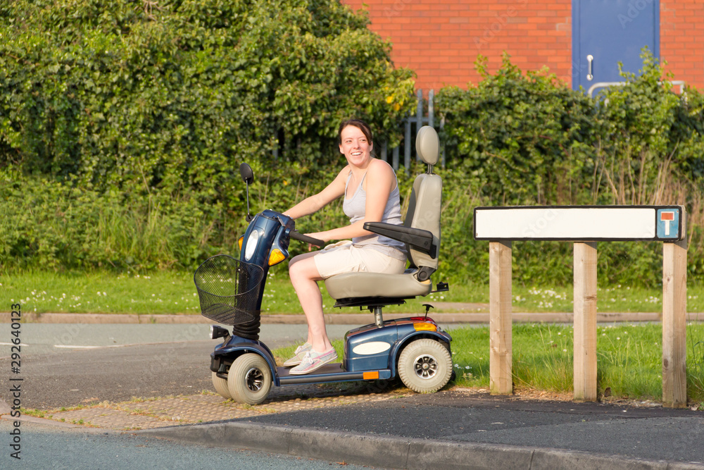 Young disabled woman on a mobility scooter in the summer smiling. Young disabled woman on a mobility scooter in the summer smiling.
