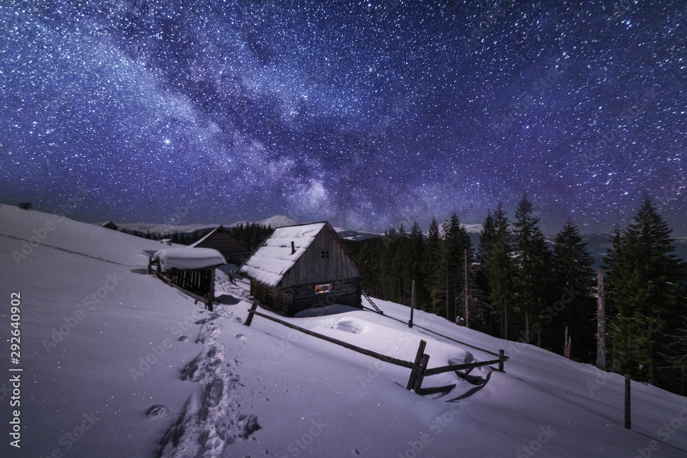Obraz premium Fairytale landscapes of the winter Carpathian Mountains with a charming milky way in the sky tourist tents and snowy houses in the valleys