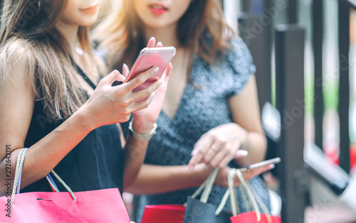 Cropped shot of two attractive women using smartphone while shopping at the mall.