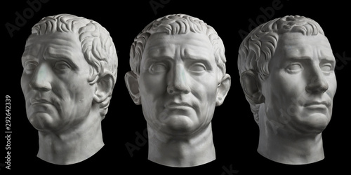 Three gypsum copy of ancient statue head of Guy Julius Caesar isolated on black background. Plaster sculpture man face.