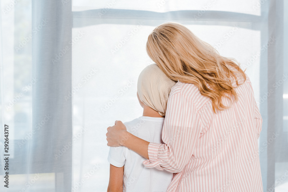 back view of mother hugging daughter in head scarf