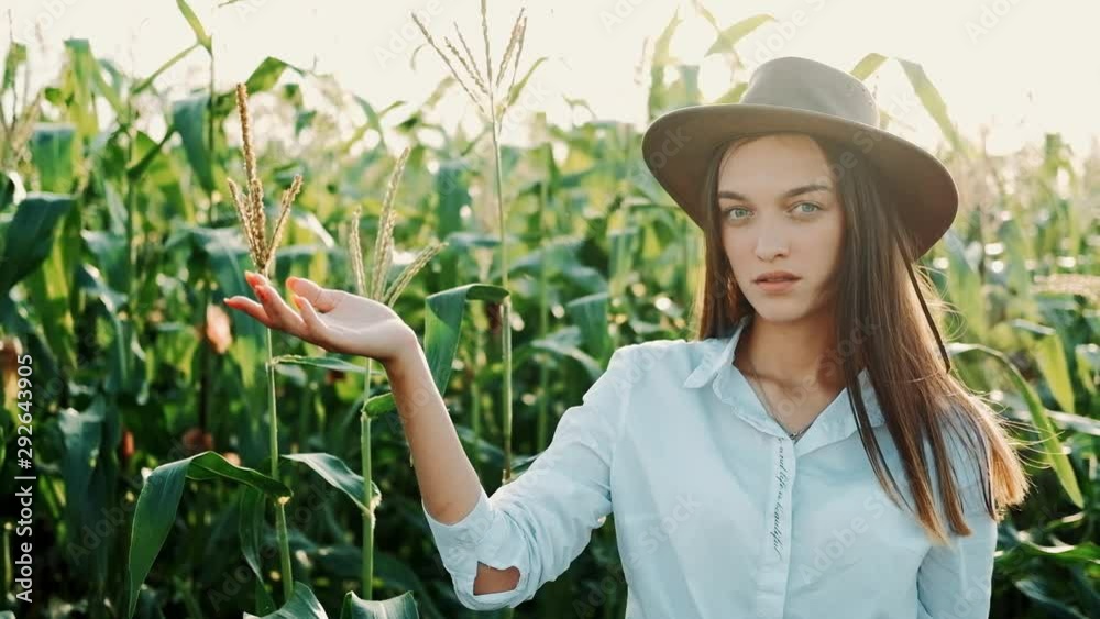 Portrait of Young Farmer girl in Hat Shows Up with Hand Her Corn Field