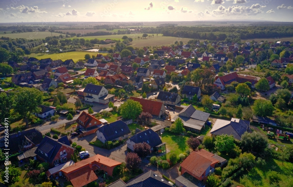 Oblique aerial view of a village in Germany with detached houses, yarns, lawns and roads