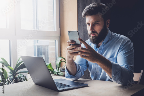 Office worker relaxing, playing online games on smartphone. Man downloading interesting apps on his mobile device. Home-based freelancer looking for instructions on its work. Male adult checking email