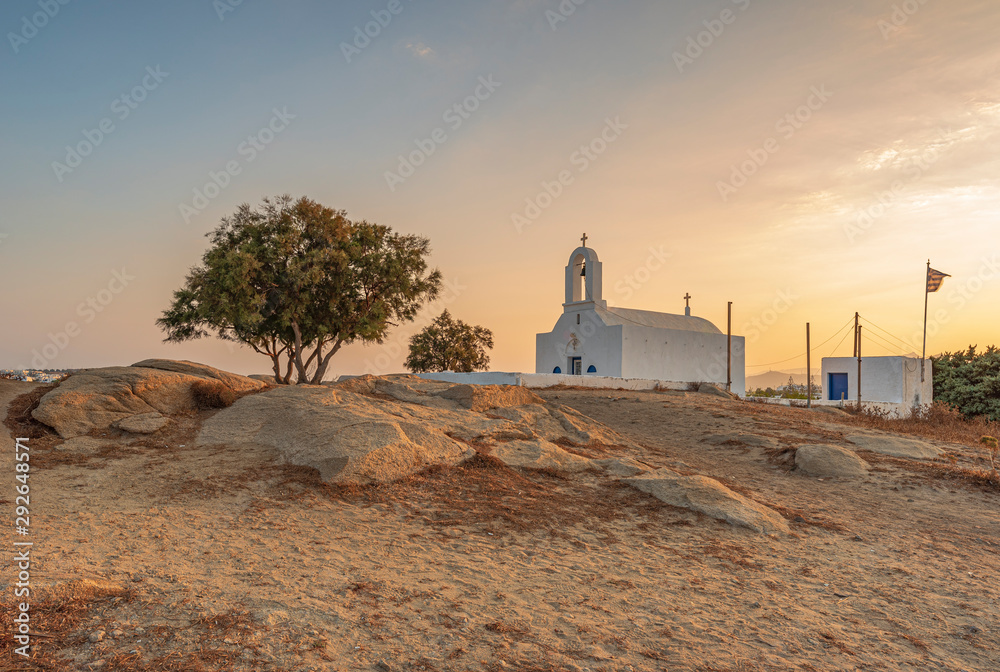 Il sole sorge dietro la piccola cappella di Agios Nikolaos nel villaggio di Agia Anna, isola di Naxos GR	