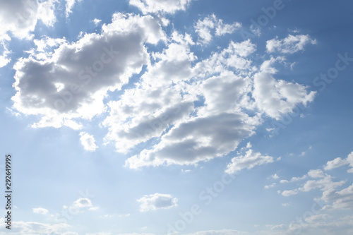 light blue sky with white clouds highlighted closeup in the rays of a bright sun