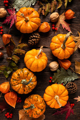 Autumn decorative pumpkins with fall leaves on wooden background. Thanksgiving or halloween holiday, harvest concept. Top view, copy space. Greeting card