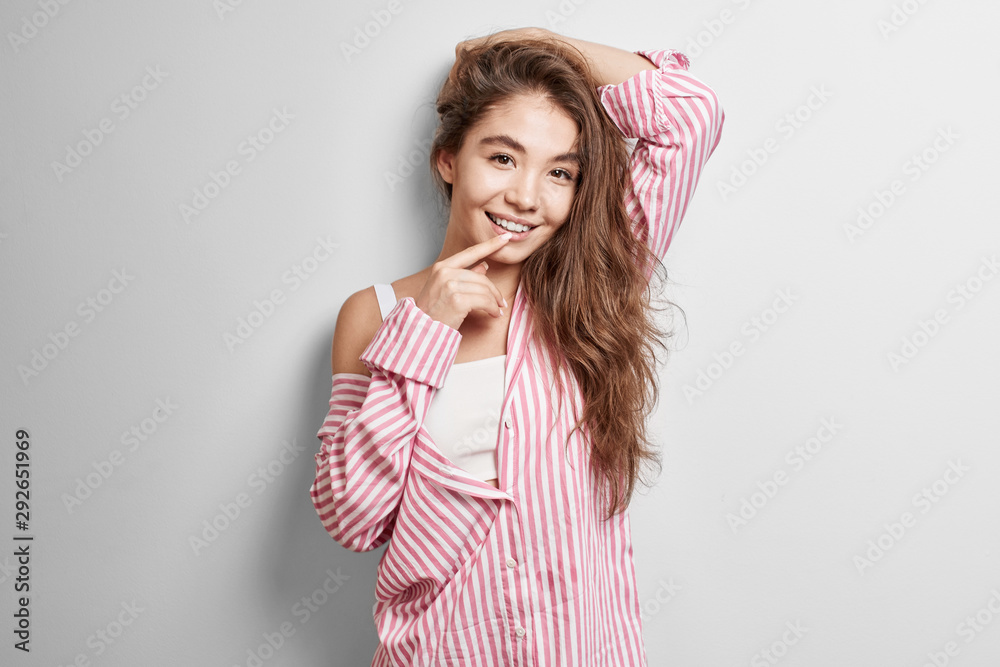 Portrait of a sexy Kazakh model girl with long brunette hair on a white background flirts and bites her finger Portrait of a sexy Kazakh model girl with long brunette hair on a white background flirts and bites her finger