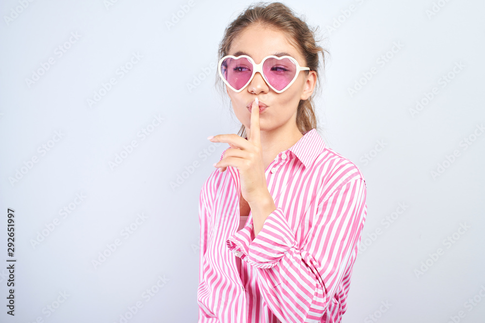 Asian Kazakh girl put her index finger to lips, shh. Concept keep quiet, secret, silence