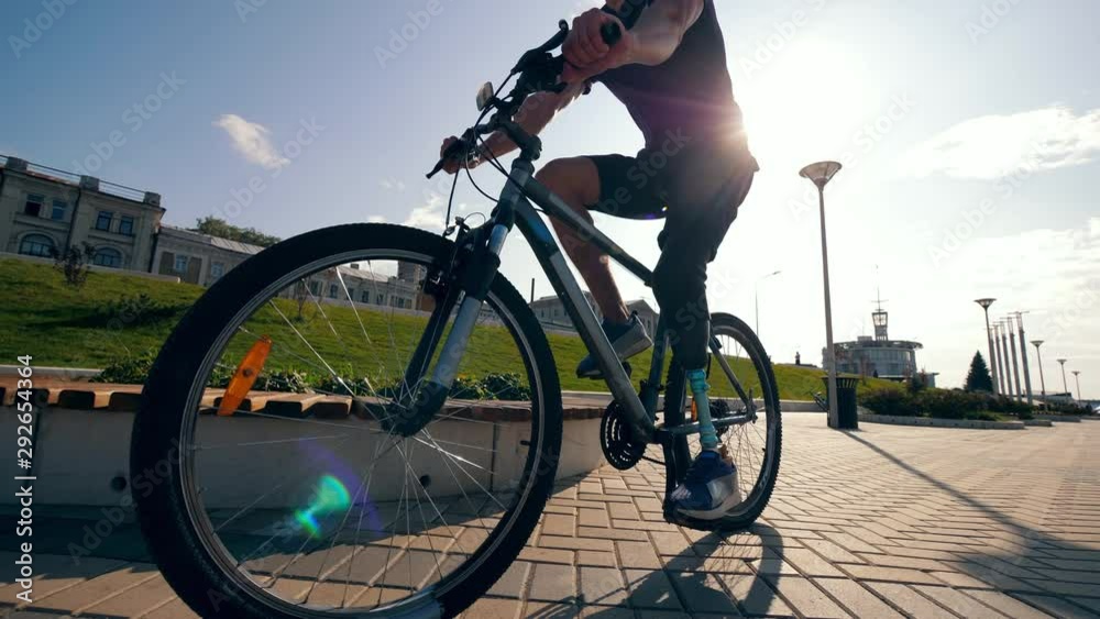 Athlete with a bionic leg is riding a bike along the road Athlete with a bionic leg is riding a bike along the road