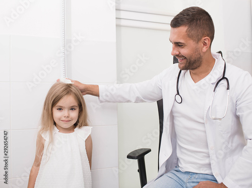The doctor measures the growth of a little girl. Pediatrician and little patient