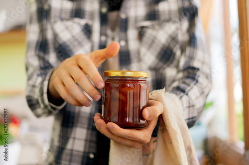 person hand holding a homemade jar of jam with fruits, glass pot