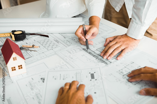 Architects engineer working with blueprints on table and discussing project together at the meeting in the office.