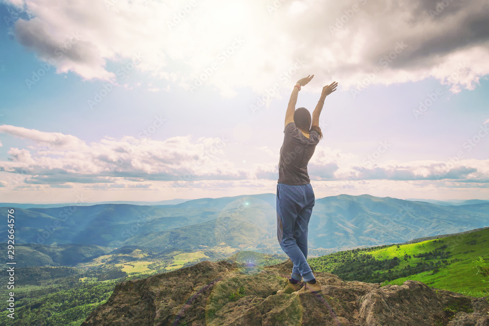 Girl on the mountain raised her hands to the sunny cloudy sky. Tourism. Hiking.