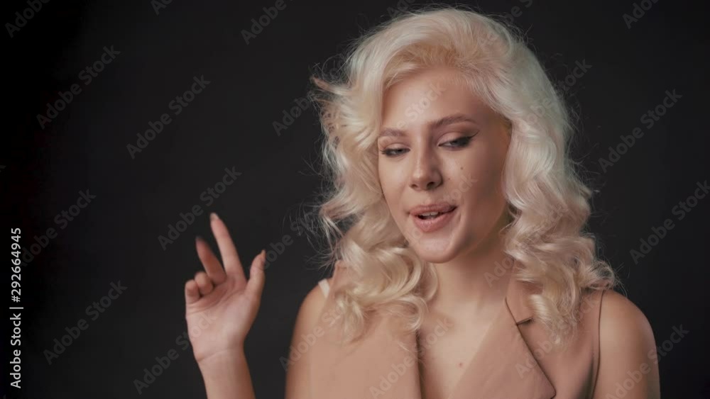 Portrait of a woman smiling and saying hello. Light hair, smooth skin.