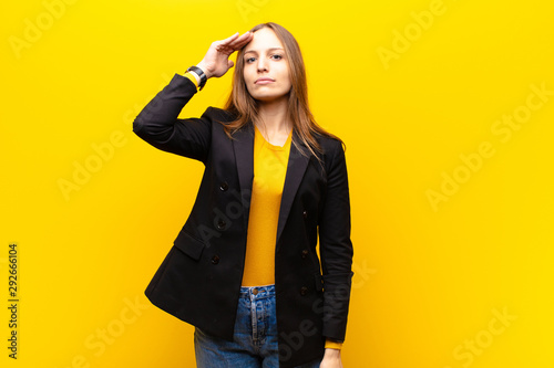 young pretty businesswoman greeting the camera with a military salute in an a...
