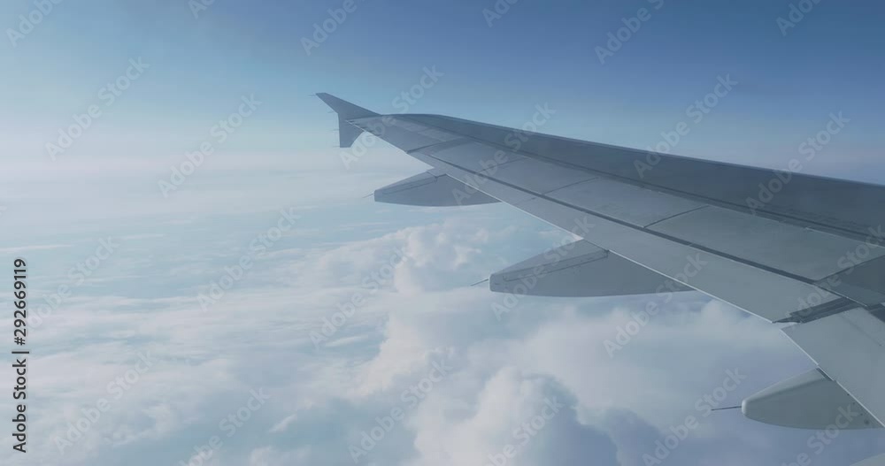 View on blue sky and fluffy white clouds through the window of the aircraft. Scenic view from flying airplane. View on blue sky and fluffy white clouds through the window of the aircraft. Scenic view from flying airplane.